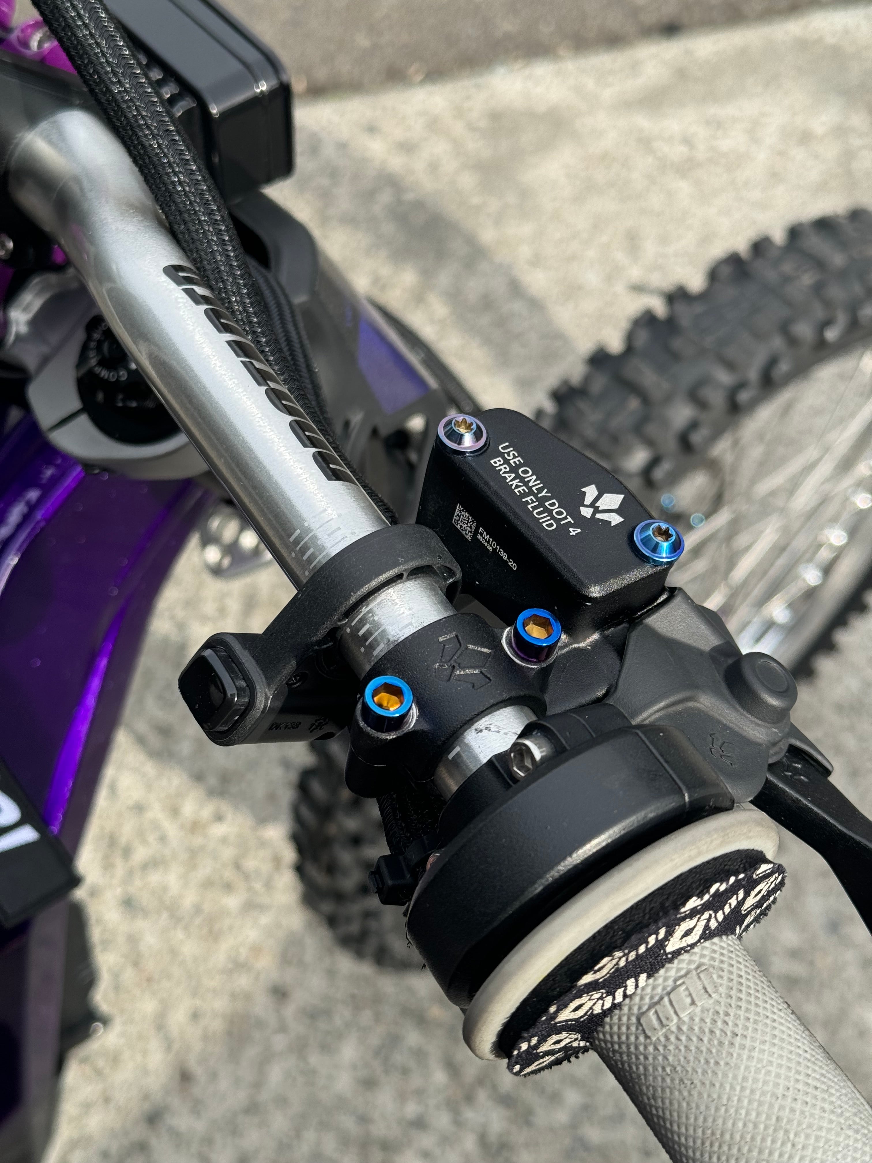 Mxp_designs Formula titanium brake mount bolts installed on a bicycle, showing sleek, lightweight hardware for bike braking system.