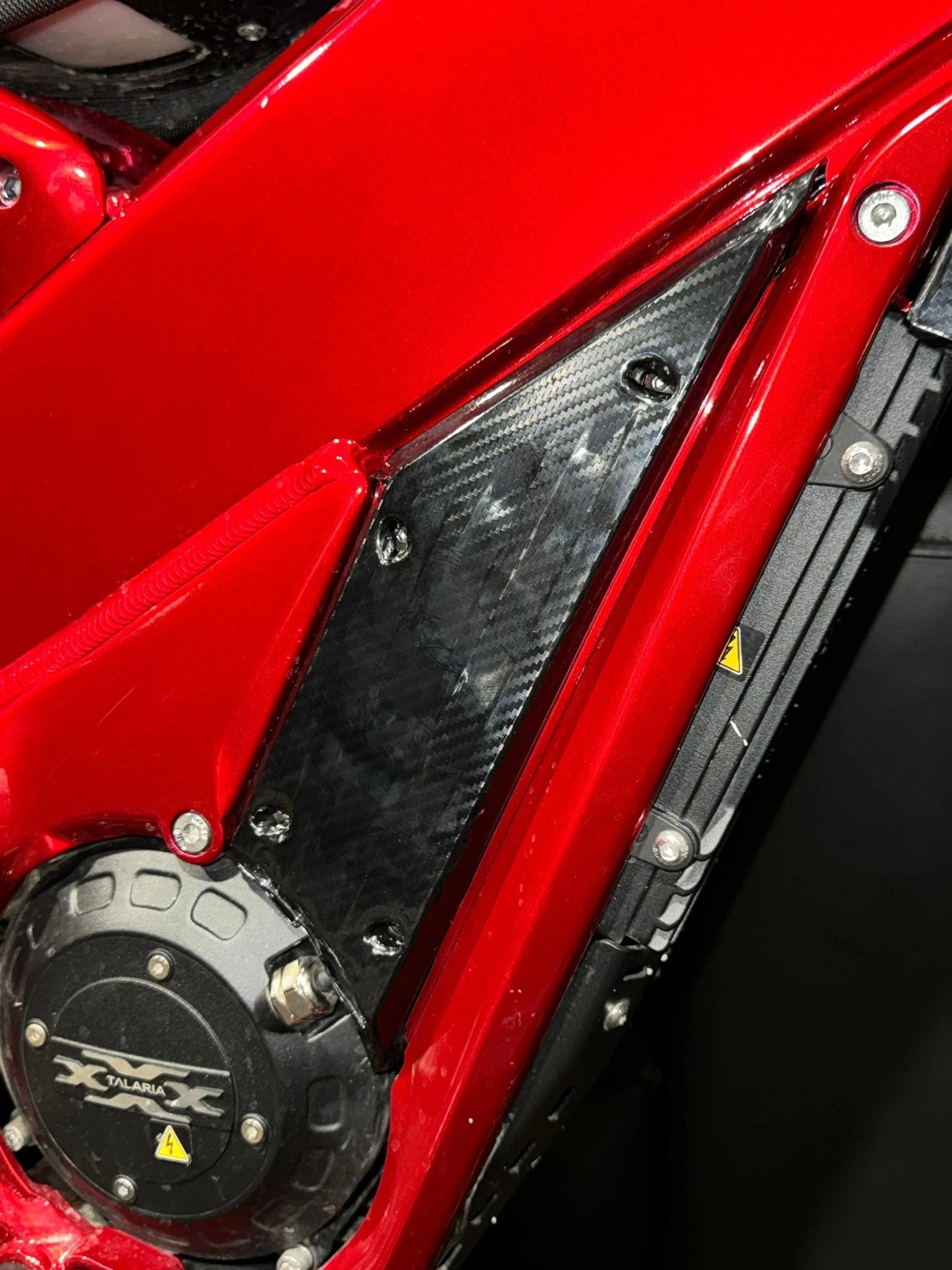 MXwraps Talaria XXX Carbon Fiber Wrap Kit vinyl wrap showing textured carbon fiber pattern on a vehicle surface.